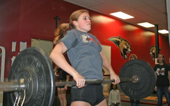 Grace Dickinson, a senior at Cardinal Mooney High School in Sarasota, Fla., performs a dead lift to an overhead press with 95 pounds as her coaches observe her Dec. 19, 2018. This is the inaugural year for the girls weightlifting team at the Florida Catholic school.