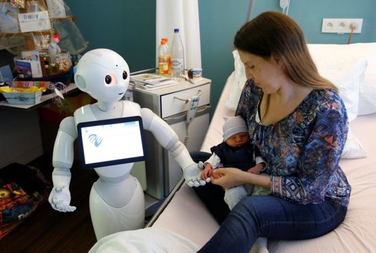 "Pepper" the robot, a humanoid robot designed to welcome and take care of visitors and patients, holds the hand of a new born baby next to his mother at AZ Damiaan hospital in Ostend, Belgium, June 16, 2016. The Vatican's Pontifical Academy for Life has added robotics to its list of specialized areas of study.