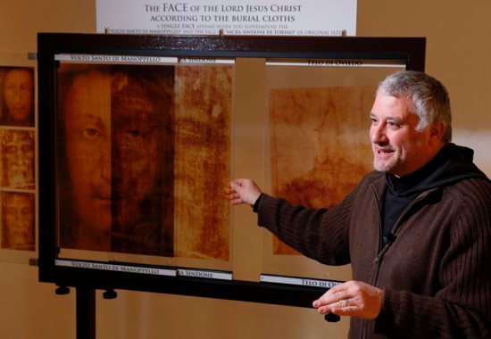 Capuchin Father Paolo Palombarini, parochial vicar of the Shrine of the Holy Face, explains the compatibility between the Holy Face of Manoppello and the Shroud of Turin as he overlays copies of the images in the museum at the shrine in Manoppello, Italy, Jan. 11. Devotees believe that the Holy Face of Manoppello was one of the burial shrouds that covered the face of Jesus in the tomb and that the image was formed miraculously at the moment of the resurrection.