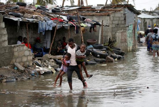 A man carries his children through floodwaters in the aftermath of Cyclone Idai in Beira, Mozambique, March 23, 2019. More than 2 million people in Mozambique, Zimbabwe and Malawi have been affected by a cyclone that has killed more than 700 people, with hundreds still missing in Mozambique and Zimbabwe. 