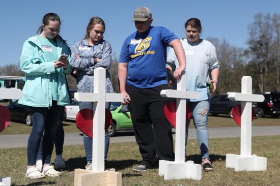 People in Beauregard, Ala., stand in front of crosses March 6, 2019, to honor the victims who died in the two tornadoes.