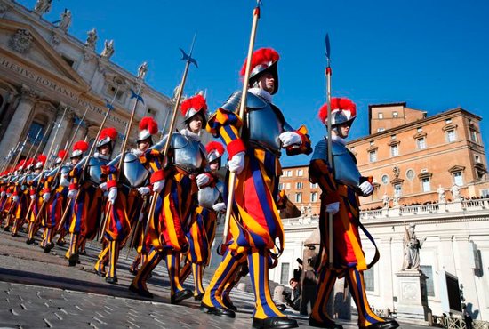 Swiss Guards march in St. Peter's Square at the Vatican Dec. 25, 2017. To better protect minors and vulnerable adults from all forms of abuse and exploitation, Pope Francis approved a new law and a set of safeguarding guidelines for Vatican City State and the Roman Curia. 
