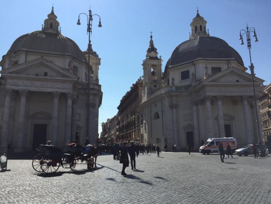 Pedestrians pass the Basilica of Santa Maria in Montesanto and the Church of Santa Maria dei Miracoli in Rome’s Piazza del Popolo March 28, 2019. Neither church is considered a parish, although both have regularly scheduled Masses each day. The Diocese of Rome has decided that the Easter Triduum should be celebrated only in parish churches, not other churches, chapels or oratories.
