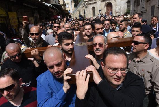 Mousa Kamar, front right, at the head of the cross, and his son Youssef, diagonal to his father, in the corner of the cross, helps carry a large wooden cross during the Good Friday procession on the Via Dolorosa in Jerusalem's Old City March 25, 2016. Mousa Kamar and his sons are carrying on the tradition of his grandfather and father, carrying the cross on Good Friday.