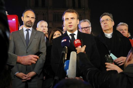 French President Emmanuel Macron speaks to the media alongside Prime Minister Edouard Philippe, left, and Paris Archbishop Michel Aupetit, outside Notre Dame Cathedral April 16, 2019, after a fire broke out in the iconic Paris structure. Officials said the cause was not clear, but that the April 15 blaze could be linked to renovation work. 