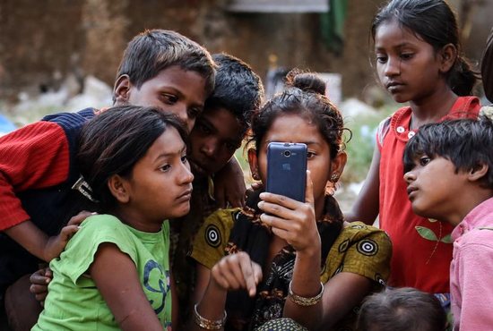 Indian children watch a movie on a cellphone on the roadside in Mumbai Jan. 20, 2016. While digital communications and social media can be used as a tool of evangelization and a place of dialogue with others, they also can be lonely environments where young people fall prey to humanity's worst vices, Pope Francis wrote in his new apostolic exhortation to young people, "Christus Vivit" ("Christ Lives"). 
