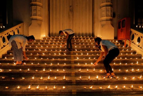 Young people light candles near the closed door of a church in Colombo, Sri Lanka, April 28, 2019, during a vigil in memory of the victims of a string of suicide bomb attacks across the island on Easter. 