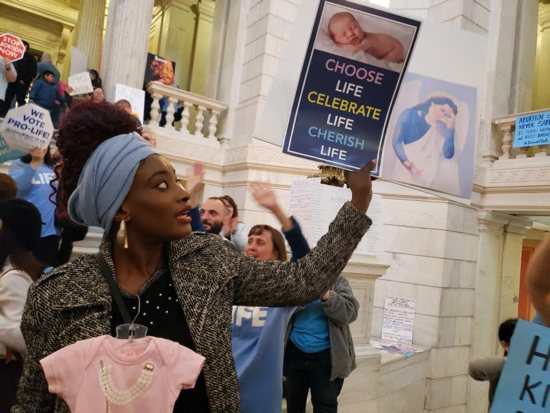 Elizabeth Koroma of Providence, R.I., holds a pro-life sign in the rotunda of the Rhode Island Statehouse late May 14, 2019, to protest a Senate bill aimed at expanding legal abortion in Rhode Island. Hundreds of activists who gathered at the Statehouse erupted into cheers as news spread that the committee voted 5-4 against the measure, which supporters said would have enshrined Roe v. Wade into state law.