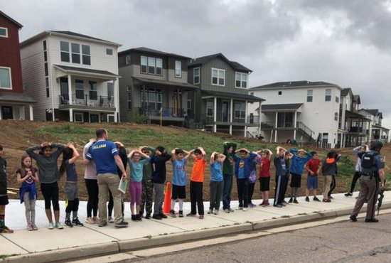 A photo obtained via social media shows school children standing in line with an armed police officer near STEM School Highlands Ranch during a shooting incident in at the Colorado school May 7, 2019. At least one student was killed and eight others injured in the shooting at the charter school in an affluent Denver suburb. Two suspects, both students at the school, were captured at the scene, authorities said. Two of the injured were listed in serious condition.