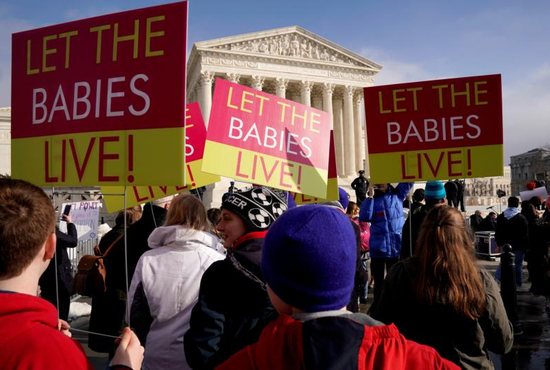 Pro-life supporters hold signs outside the U.S. Supreme Court