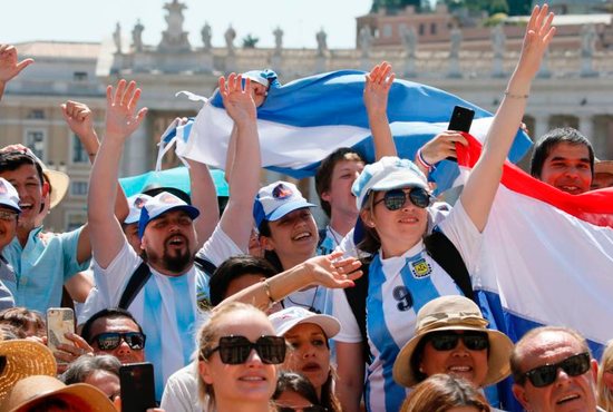 People wearing Argentina's colors cheer as Pope Francis leads his general audience