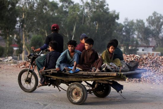 Boys from an Afghan refugee family ride on a motorcycle cart