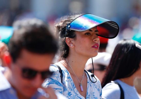 A woman wears a sun visor as she waits for Pope Francis to lead the Angelus 