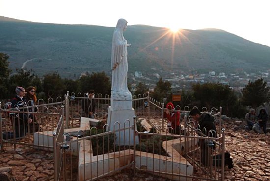 Pilgrims pray around a statue of Mary on Apparition Hill in Medjugorje