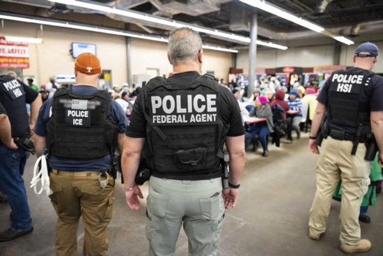 U.S. Immigration and Customs Enforcement officers look on after executing search warrants and making some arrests 
