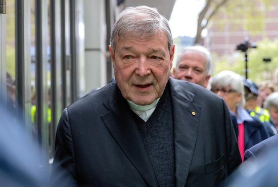 Australian Cardinal George Pell is surrounded by police as he leaves the Melbourne Magistrates Court in Australia