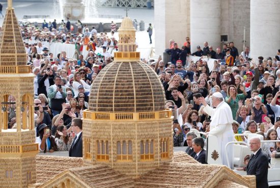 Pope Francis passes a model of a church