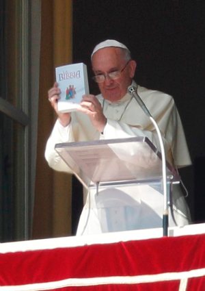 Pope Francis holds up a Bible 
