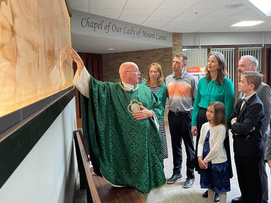 Father Brian Lynch, associate pastor of Transfiguration in Oakdale, explains details in an approximate half-size replica of the shroud of Turin that is displayed in the church’s Elijah Gallery, located between the main church and the chapel. With Father Lynch, clockwise, are Transfiguration parishioner Mary Byrne, Pete Quimby, and the Oakes family, parishioners of St. Michael in Stillwater: Renee and Matthew with children Evelyn and Henry. 