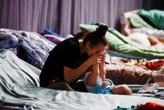 A woman in Przemysl, Poland, plays with her child March 9, 2022, in a sports hall of a high school transformed into temporary accommodations for people fleeing the Russian invasion of Ukraine.