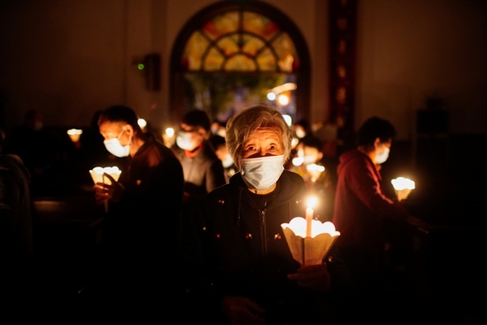 Worshippers holding candles and wearing protective masks pray during the Easter Vigil in Shanghai April 3, 2021. Bishop Joseph Zhang Weizhu of Xinxiang -- a Vatican-approved Chinese prelate --remains in detention more than one year after his arrest, accused of violating the communist country's regulations on religious affairs.