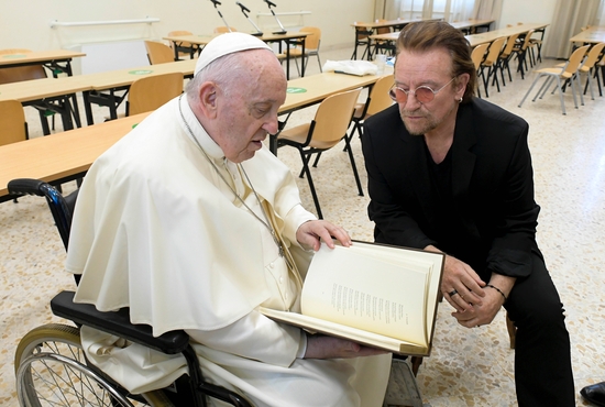 Pope Francis talks with U2 singer Bono before a meeting of Scholas Occurentes in Rome May 19, 2022. The event was for the launch of the "Laudato Si' School," a yearlong project of Scholas young people to develop projects to promote protection of the environment. 