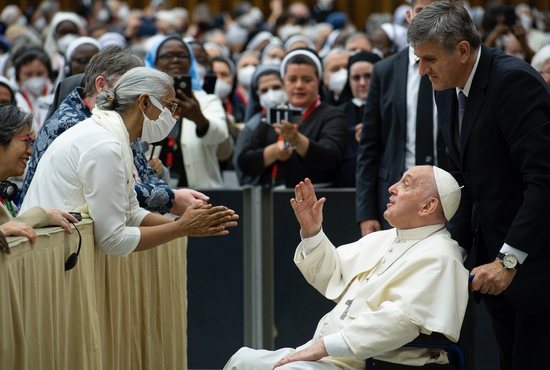 Pope Francis is pushed in a wheelchair by his aide, Sandro Mariotti, as he greets participants in the plenary assembly of the women's International Union of Superiors General (UISG) at the Vatican May 5, 2022. 