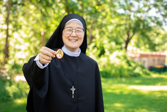 Sister Janet Kobayashi, a sister of Pro Ecclesia Sancta for 22 years who lives at the sisters’ convent in Bloomington, holds a Sacred Heart badge she and other sisters distribute with promise of prayers for those who keep them.