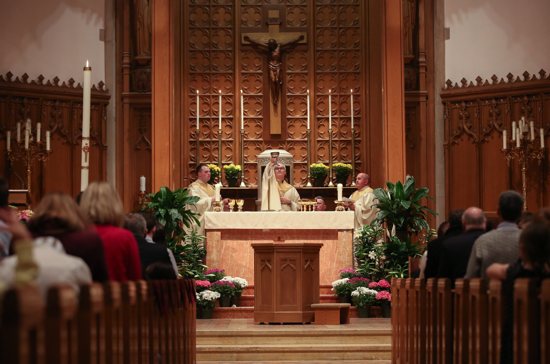 Father Patrick Hipwell, pastor of Nativity of Our Lord in St. Paul, elevates the chalice during the Easter Vigil Mass in 2018. Joining him at the altar are Father John Powers, left, who was serving at the parish at that time, and Father Allen Kuss, who was serving at The St. Paul Seminary.