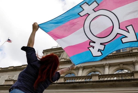 A person in New York City holds up a flag Oct. 24, 2018, to protest a policy by the then-Trump administration to define sex as an individual's status as male or female based on traits identified at birth.