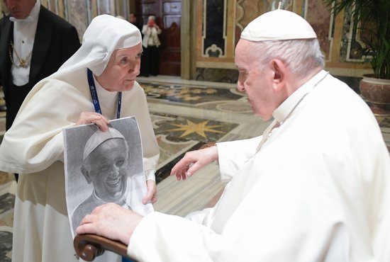Pope Francis looks at artwork of himself presented by a nun during an audience with the participants of a symposium on "Holiness Today," sponsored by the Dicastery for the Causes of Saints, at the Vatican Oct. 6, 2022.