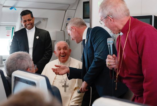 Pope Francis shares a laugh with Anglican Archbishop Justin Welby, right, while answering questions from journalists aboard the flight from Juba, South Sudan, to Rome Feb. 5, 2023.