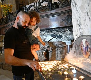 William Mabouk holds his son Yonathan, 3, while lighting a candle at the Stella Maris Carmelite monastery in Haifa, Israel, during a July 30, 2023, protest by Holy Land Christians against what they say are insufficient actions by the Israeli police in blocking some members of the Breslov ultra-orthodox sect who began arriving at the monastery in early May, claiming it is a Jewish holy site. 